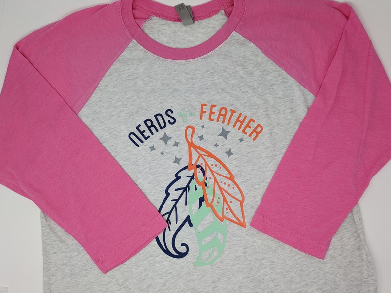 May include: A gray and pink baseball tee shirt with a graphic of two leaves and the text "NERDS of the FEATHER".