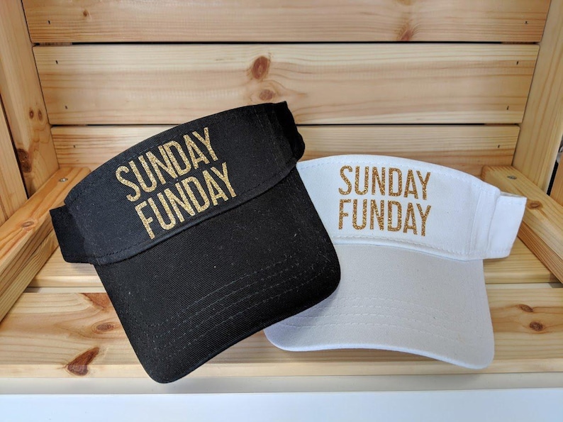 May include: Two black and white visors with gold glitter lettering. The black visor says "SUNDAY FUNDAY" and the white visor says "SUNDAY FUNDAY".