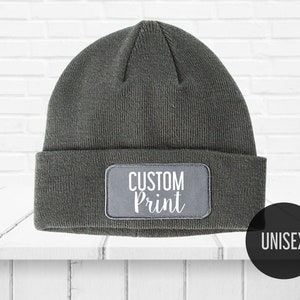 May include: Gray beanie with a white patch that says "CUSTOM Print" and the word "UNISEX" in a black circle.