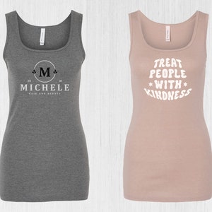 May include: Two tank tops, one gray with a white logo that says "Michele Hair and Beauty" with a stylized "M" and the numbers "20" and "21" on either side of the "M", and the other a light pink tank top with the text "Treat People With Kindness" in white.