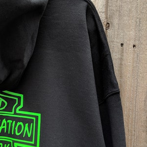 May include: Black hooded sweatshirt with a green graphic of a motorcycle club logo that says "Wicked Transportation" on the back.