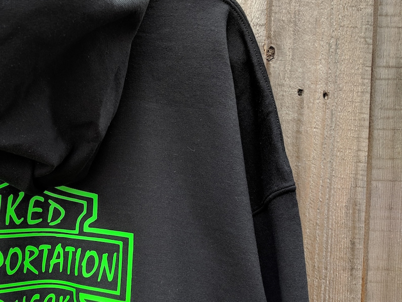 May include: Black hooded sweatshirt with a green graphic of a motorcycle club logo that says "Wicked Transportation" on the back.