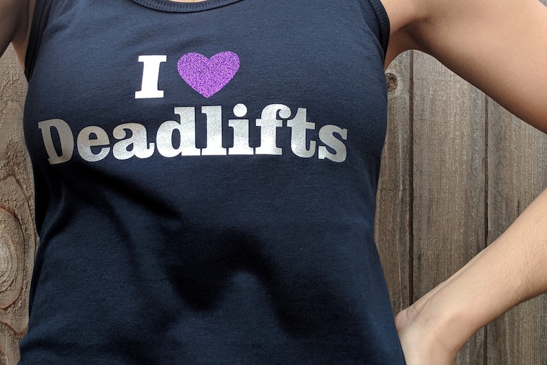 May include: A black tank top with a silver glitter design that says "I heart Deadlifts" with a purple glitter heart.