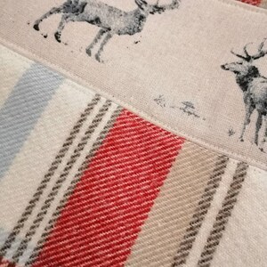 Puede incluir: Primer plano de una tela con un patr&oacute;n de cuadros rojos, blancos y grises. La tela tiene un dise&ntilde;o impreso de dos ciervos, uno con cuernos y otro sin.