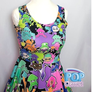 May include: A black sleeveless dress with a colorful print of cartoon squids and paint splatters. The dress has a fitted bodice and a flared skirt. The print features various colors, including pink, blue, green, orange, and purple. The dress has a scoop neck and a racerback style. The dress is made of a soft, stretchy fabric. The dress is perfect for fans of the popular video game Splatoon.