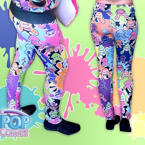 Peut inclure: Leggings color&eacute;s avec un motif r&eacute;p&eacute;t&eacute; de personnages de calamars de dessin anim&eacute;. Les leggings sont noirs avec des accents roses, bleus, verts, oranges et jaunes. Les leggings sont pr&eacute;sent&eacute;s sur un mannequin avec un fond vert.
