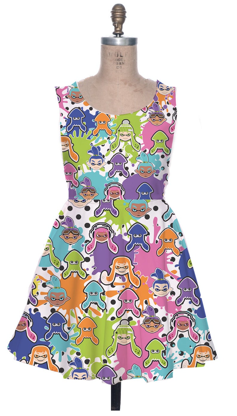 May include: A white sleeveless dress with a colorful print of cartoon characters from the video game Splatoon. The characters are wearing different colored outfits and have different colored ink splatters around them.