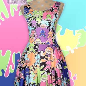May include: A black sleeveless dress with a colorful print of cartoon squid characters and paint splatters. The dress has a fitted bodice and a flared skirt. The print features a variety of colors, including pink, blue, green, orange, and purple.