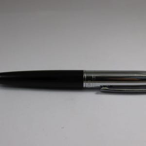 Pode incluir: Uma caneta preta e prateada com acabamento cromado. A caneta tem um clipe na parte superior e um corpo preto.