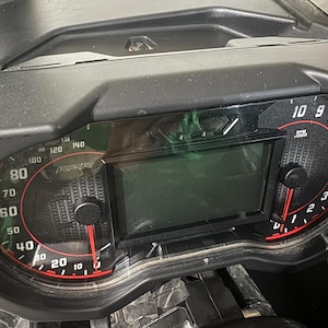 May include: A black dashboard with two gauges. The left gauge is a speedometer with a red needle pointing to 30 mph. The right gauge is a tachometer with a red needle pointing to 1,000 RPM. The gauges have a black background with white numbers and red needles.