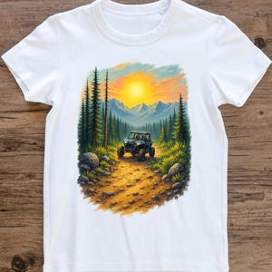 Könnte beinhalten: Weißes T-Shirt mit einem farbenfrohen Grafikdesign eines Geländewagens, der auf einem Waldweg fährt. Der Hintergrund zeigt einen Sonnenuntergang über Bergen und Bäumen. Das Design ist mittig auf dem T-Shirt platziert.