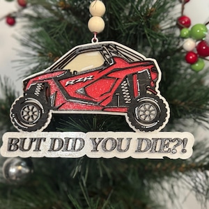 Op de afbeelding: Rood en zwart RZR off-road voertuig kerstversiering met de tekst "But did you die?"