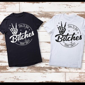 以下が含まれることがあります： 黒と白の2枚のTシャツ。デザインは、ピースサインをする骸骨の手、太字の「Bitches」という単語、そして円状に配置された「Time To Ride Ridin' Dirty」というテキストが特徴です。