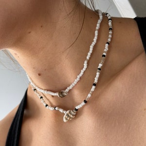 May include: Two layered necklaces with white and black beads and shell charms.