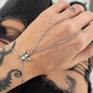 Puede incluir: Una taza de cerámica blanca con un asa negra y el texto "But First, Coffee" en negrita negra. La taza se encuentra sobre un fondo borroso, sugiriendo un ambiente acogedor.