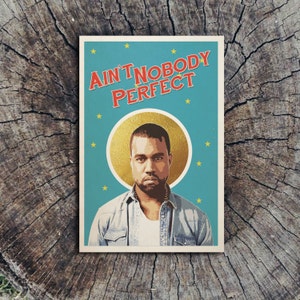 May include: A blue and gold poster with a picture of Kanye West and the text "Ain't Nobody Perfect".