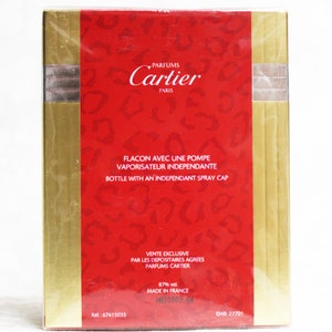 Pu&ograve; includere: Scatola rossa e dorata con il testo "PARFUMS Cartier PARIS" e "FLACON AVEC UNE POMPE VAPORISATEUR INDEPENDANTE BOTTLE WITH AN INDEPENDANT SPRAY CAP". La scatola include anche il testo "VENTE EXCLUSIVE PAR LES DEPOSITAIRES AGREES PARFUMS CARTIER 87% vol. MADE IN FRANCE H810009.64 EMB. 27701" e il numero di riferimento "Ref.: 67415035".