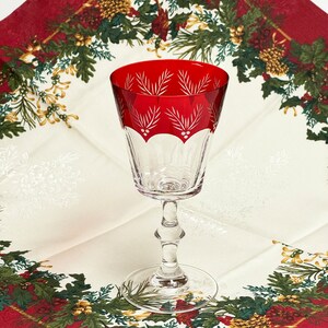 May include: A red wine glass with a clear stem and base. The glass has a red, white, and green design with a holly and berry pattern.