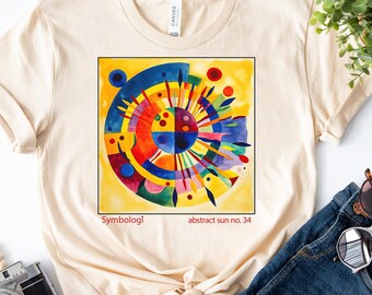 May include: A beige t-shirt featuring a colourful abstract sun design. The design is a circle with a yellow background and various colours, including red, blue, green, and pink. The text "Symbologi abstract sun no. 34" is printed below the design.