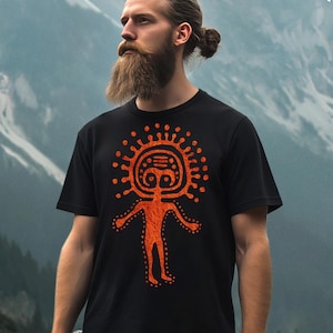 May include: A black t-shirt with an orange stylized human figure design. The figure has a circular head with two eyes and a mouth. The figure is surrounded by a circle of dots.