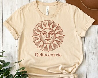 May include: A beige t-shirt with a vintage illustration of the sun with a face and the word "Heliocentric" printed below it.