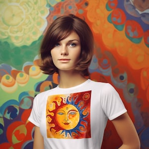 May include: A white t-shirt featuring a colourful sun graphic. The sun has a face with blue eyes and a yellow smile. The background of the sun is red and orange.