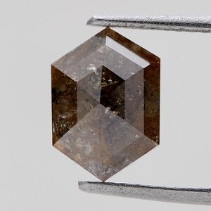 Könnte beinhalten: Ein sechseckiger, brauner, facettierter Diamant mit einem grauen, trüben Inneren.