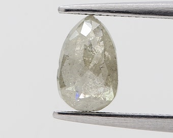 Puede incluir: Un diamante en forma de pera, de color gris claro, sujeto con pinzas plateadas. El diamante tiene múltiples facetas, que reflejan la luz. La gema es de color neutro.