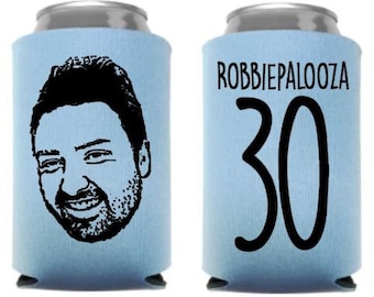 May include: Two light blue can coolers. One cooler features a black and white illustration of a man's face. The other cooler has the text "ROBBIEPALOOZA 30" in black.