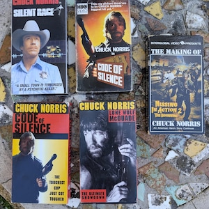 May include: Collection of vintage VHS tapes featuring Chuck Norris movies. Titles include "Silent Rage," "Code of Silence," "Lone Wolf McQuade," and "Missing in Action 2." The tapes have colorful covers with action shots and movie titles.