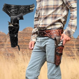 May include: A black leather gun holster and belt set with intricate floral tooling. The set includes a leg strap and a cartridge holder. A second brown leather holster and belt set with floral tooling is also shown.