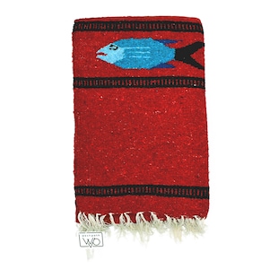 May include: Red Mexican blanket with a blue and black fish design. The blanket has black stripes and white fringe.