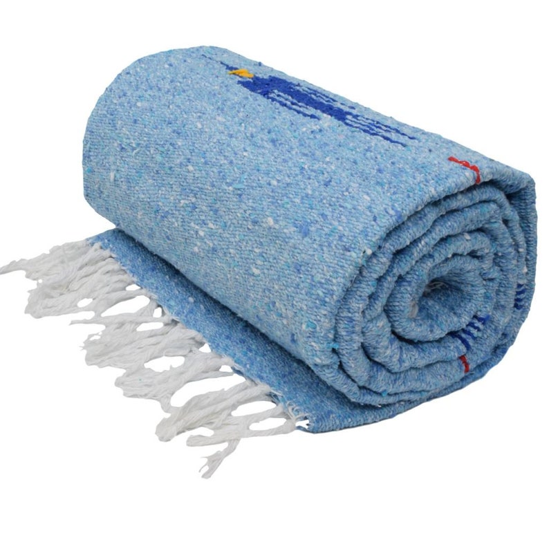 K&ouml;nnte beinhalten: Eine gerollte blaue und wei&szlig;e gewebte Decke mit wei&szlig;en Fransen. Die Decke hat ein buntes Design mit roten, blauen und gelben Akzenten.
