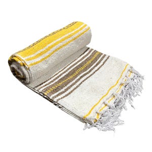 May include: Rolled-up woven blanket with yellow, brown, and white stripes. The blanket has a fringed edge and is made of a soft, textured material. The rolled portion displays yellow and white stripes.