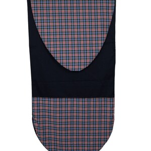May include: A plaid fabric item with a navy blue backing. The plaid pattern features a combination of red, blue, and black lines. The item has a curved bottom and a curved top section, with a solid navy blue band in the middle.