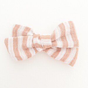 May include: A brown and white striped fabric bow. The bow is tied in a knot and has a soft, textured look.