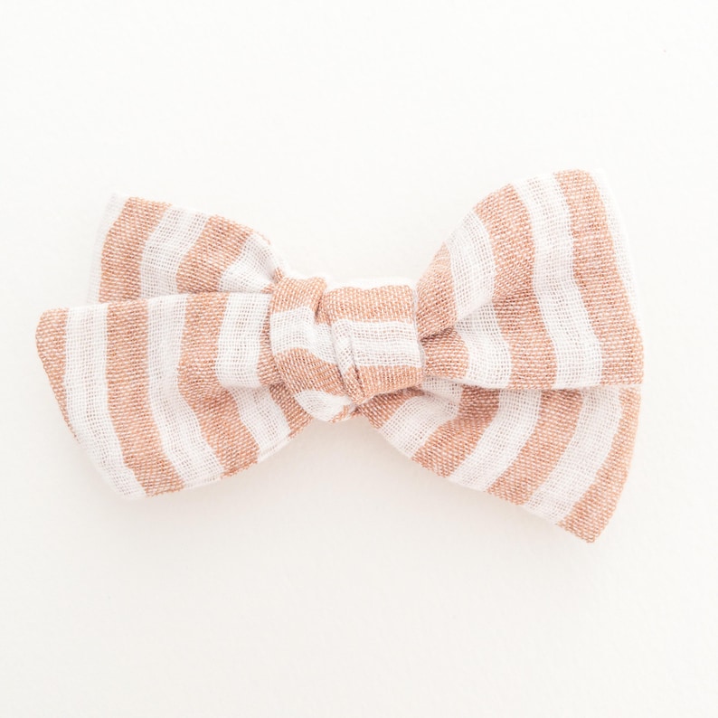 May include: A brown and white striped fabric bow. The bow is tied in a knot and has a soft, textured look.