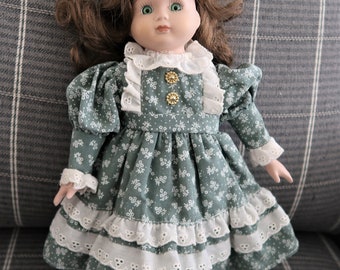 Vintage  porcelain and cloth doll with green eyes and a green and eyelet dress