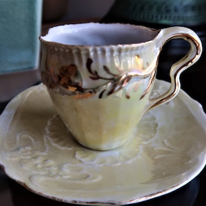 Antique crimped demitasse cup and saucer in lusterware with hand painted gold floral design