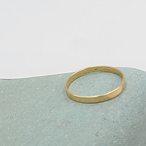 May include: A simple gold band ring on a light blue stone.