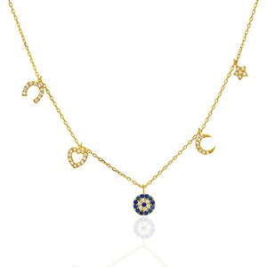 Puede incluir: Un collar de oro con una variedad de dijes, incluyendo una herradura, un coraz&oacute;n, una luna creciente, una estrella y un dije de ojo azul malvado. Los dijes est&aacute;n todos engastados con piedras de circonita c&uacute;bica transparentes.