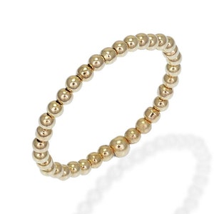 May include: A gold beaded ring with a simple design. The ring is made of small, round beads that are connected together to form a continuous circle.
