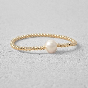 May include: A delicate gold bracelet with a single white pearl charm.