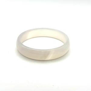 May include: A smooth, translucent off-white bangle bracelet with a polished finish. The circular jewelry piece features subtle, soft internal banding and a rounded profile, showcasing a consistent, pale, milky appearance throughout the entire band.