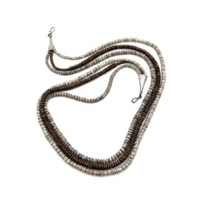 May include: A layered necklace with three strands of small, round beads in shades of brown and white. The necklace has silver-toned metal accents and clasps, and is displayed against a white background.