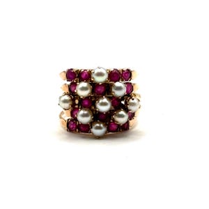 May include: A multi-band gold ring featuring a cluster of round white pearls and small round red rubies. The design incorporates several interconnected bands, creating a layered appearance with alternating gemstones set in a metallic gold frame.