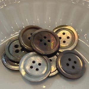 May include: A set of three ceramic mugs with a speckled, matte finish. The mugs are in shades of cream, light gray, and dark gray. Each mug has a simple, minimalist design, perfect for coffee or tea.