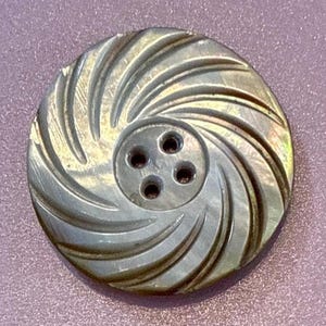 May include: A white ceramic mug with a black handle and the text "But First, Coffee" in a bold, black font. The mug is set against a blurred background, suggesting a cozy setting.