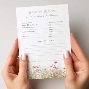 May include: A white card with the text "BABY IN BLOOM prediction and advice" and floral illustrations. The card includes sections for resemblance, birth predictions, and advice to parents. The bottom of the card has the word "love" in cursive.