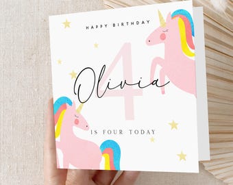 Puede incluir: Una tarjeta blanca con un unicornio rosa y un número cuatro rosa. La tarjeta dice "Feliz cumpleaños Olivia tiene cuatro años hoy".